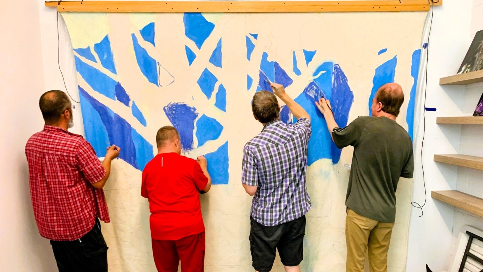 Four people painting on a large canvas
