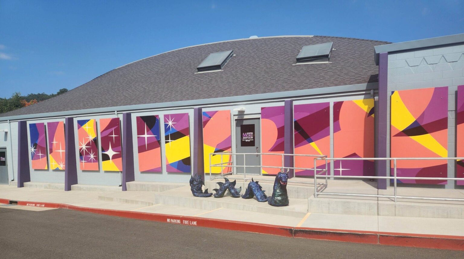 The side of MORE's building with the mural and a paper dragon in front of it