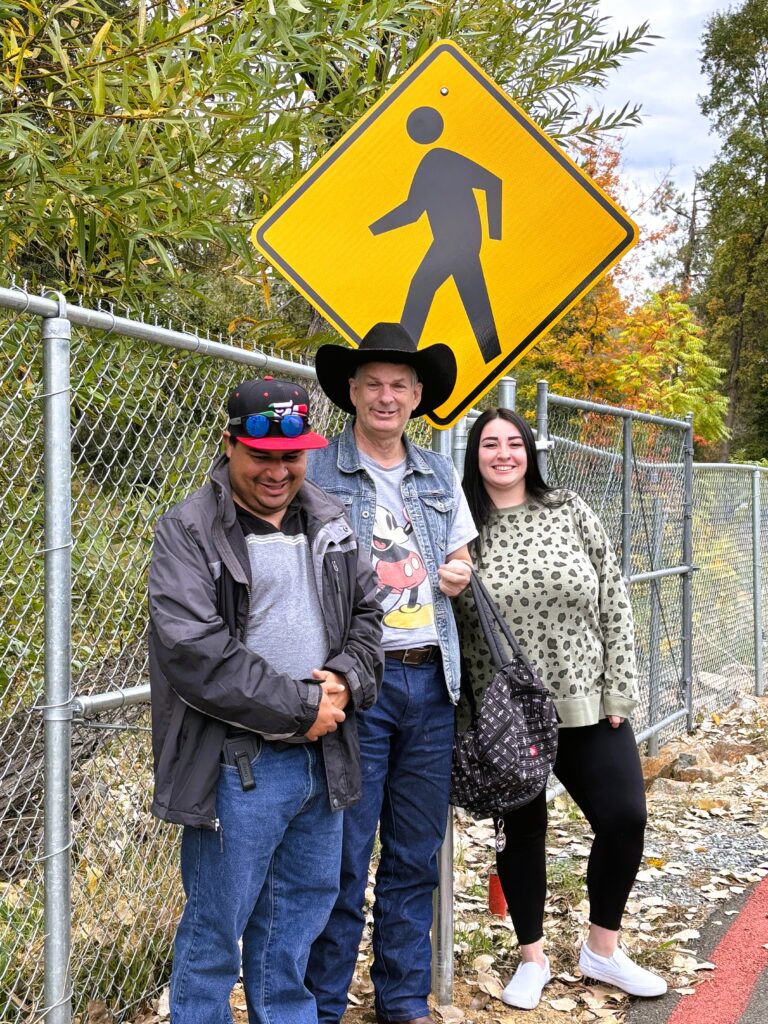 People standing by a pedestrian street sign